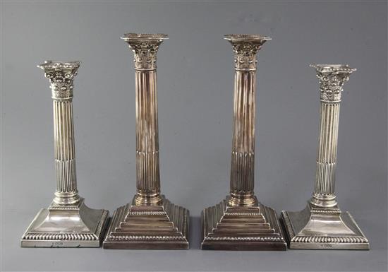 Two pairs of George V silver corinthian column candlesticks, 11.5in & 10in.